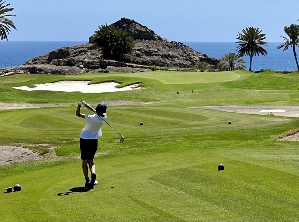 Golfkid beim Abschlag auf einem Par 3 zum Meer